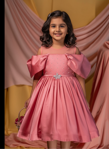 Young girl in a pink dress with bow sleeves against a pink and yellow draped backdrop